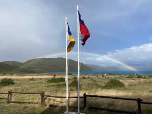 Flags in front of rainbow over lake