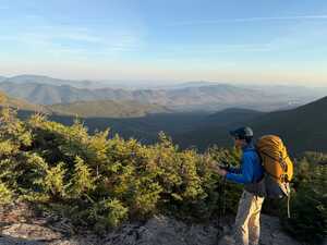Hiker in blue above mountain range in fall