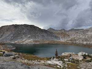Lake with stony mountains and cloudy sky in background