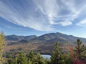 Wooded mountains with orange foliage and lake