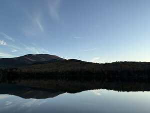 Mountain at dusk with fall foliage behind lake