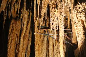 Electrical device on a rod drilled into a cave roof next to hanging stalactites