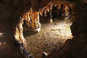 Hole in rock looking into cave with pong below filled with coins