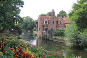 Brick cottage on a river with flower bed in foreground