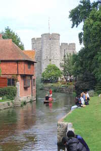 Brick cottage on a river with castle in background