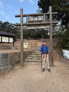 Hiker in blue in front of large trail gate