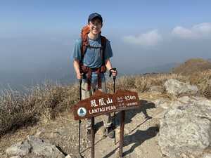 Hiker on top of mountain with sign