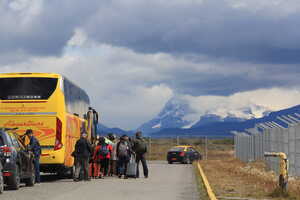 Bus in parking lot with passengers boarding and mountain behind