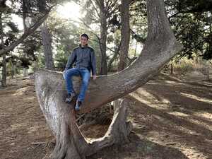 Asian man on right-angled tree trunk