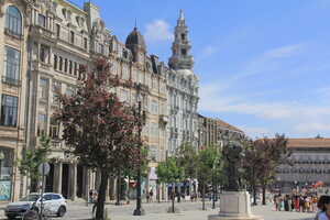 Square with statue and trees with row of ornate stone buildings behind