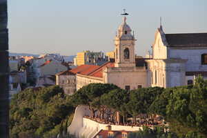 Church on city hillside with trees and people in front