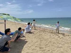 Man posing on beach with four photographers under umbrella in line