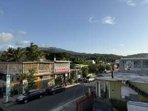 Street with low, colorful buildings and verdant mountains in the background
