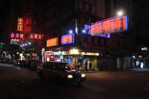 Taxi at night in front of shop with neon signs on street corner