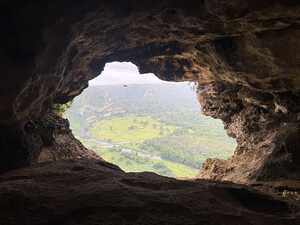 Window in rock looking out into green valley with river
