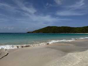 Beach with blue water and green hill behind