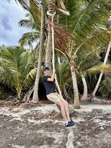 Man on rope swing from palm tree
