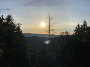 A sunset over a mountain ridge, covered with trees