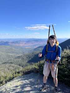 Asian man in blue with hiking poles on mountain top