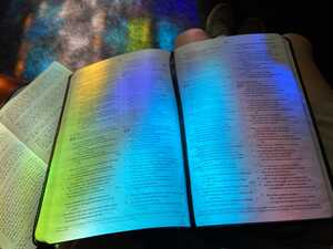 Open Bible on lap in colorful light
