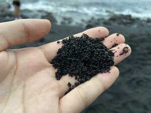 Close-up of black sand in hand