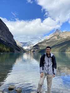 Asian man standing in front of lake and mountains