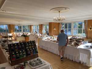 Dining room with breakfast buffet foods spread out in center on white tablecloths