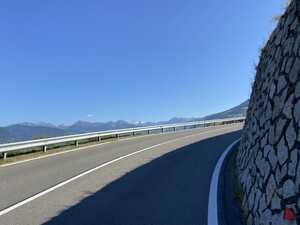 Highway bend with stone wall on the right and view of mountains on the left