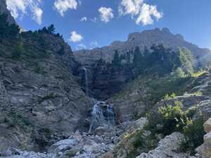 Two-tiered waterfall in the with trees above and mountain behind