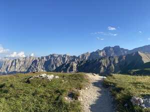 Trail leading over a hill with a mountain ridge behind