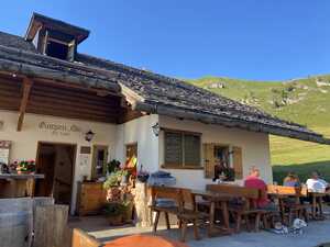 Traditional hut with outdoor benches in front of grassy hill