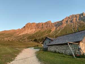 Red light reflecting off a mountain, with a path and a stone hut below in foreground