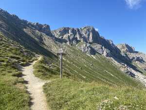 Trail in grass slopes in mountains with sign post