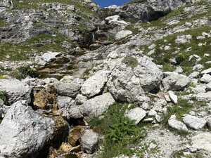 Stream flowing through rocks and grass downhill