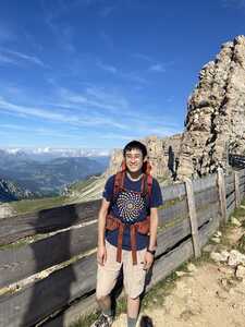 Asian man in front of fence with rock to right and valley behind