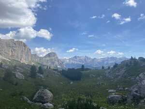 Grassy field with shrubs surrounded by mountains in the distances