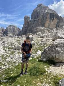 Asian man holding climbing equipment in rock field