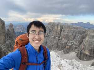 Asian man in blue in front of mountains