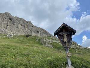 Crucifix in frontof grass and mountain