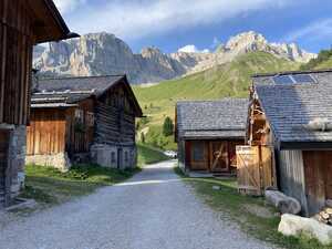 Wooden huts around gravel road in front of mountain