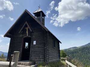 Timber chapel in front of pine forest