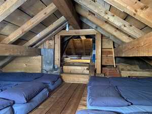 Attic dorm room with blue mats on floor and low timber ceiling