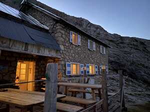 Stone hut at night in mountains with yellow lights on