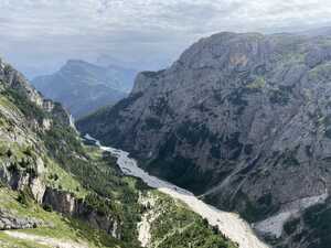 Valley with rocky mountain walls and white river of debris in middle