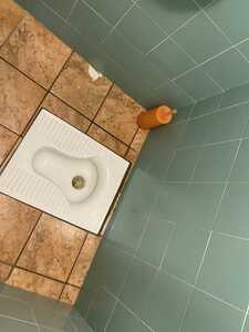 Squatting toilet with turqoise tiles on the walls