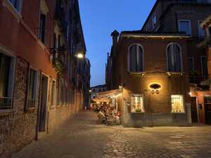 Cafe in alleyway at night with lights on and people sitting outside