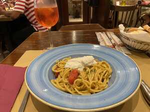 Plate of pasta with glass of orange drink on restaurant table