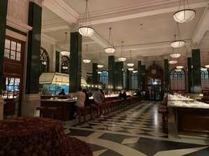 Spacious hotel lobby with dim lights, green pillars, and bar seats