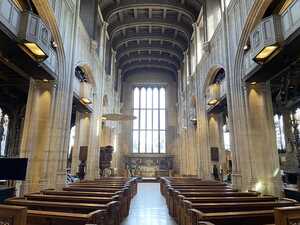 Interior of church with stone columns and wooden pews with big glass window