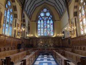 Chapel with wood panels and benches with stained glass window in rear